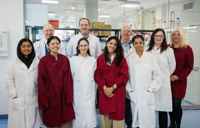 Group of people standing in a lab wearing lab coats