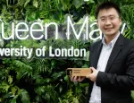 Dr Yuanwei Liu with his Early Career Researcher prize, standing in front of a green wall