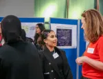 Two women speaking to each other in front of research poster boards