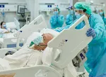 Patient on ventilator lying in hospital bed as medical professional moves his bed. Credit: xavierarnau/iStock.com