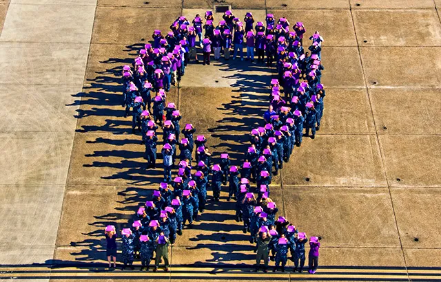 People form a purple ribbon to raise awareness for domestic violence