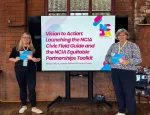 Image of two Queen Mary colleagues, each holding a booklet in their hands and one standing on either side of a TV screen, with a brick wall behind them.