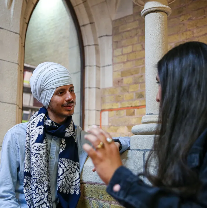2 students talking in a niche in Whitechapel library with arch and pillar behind