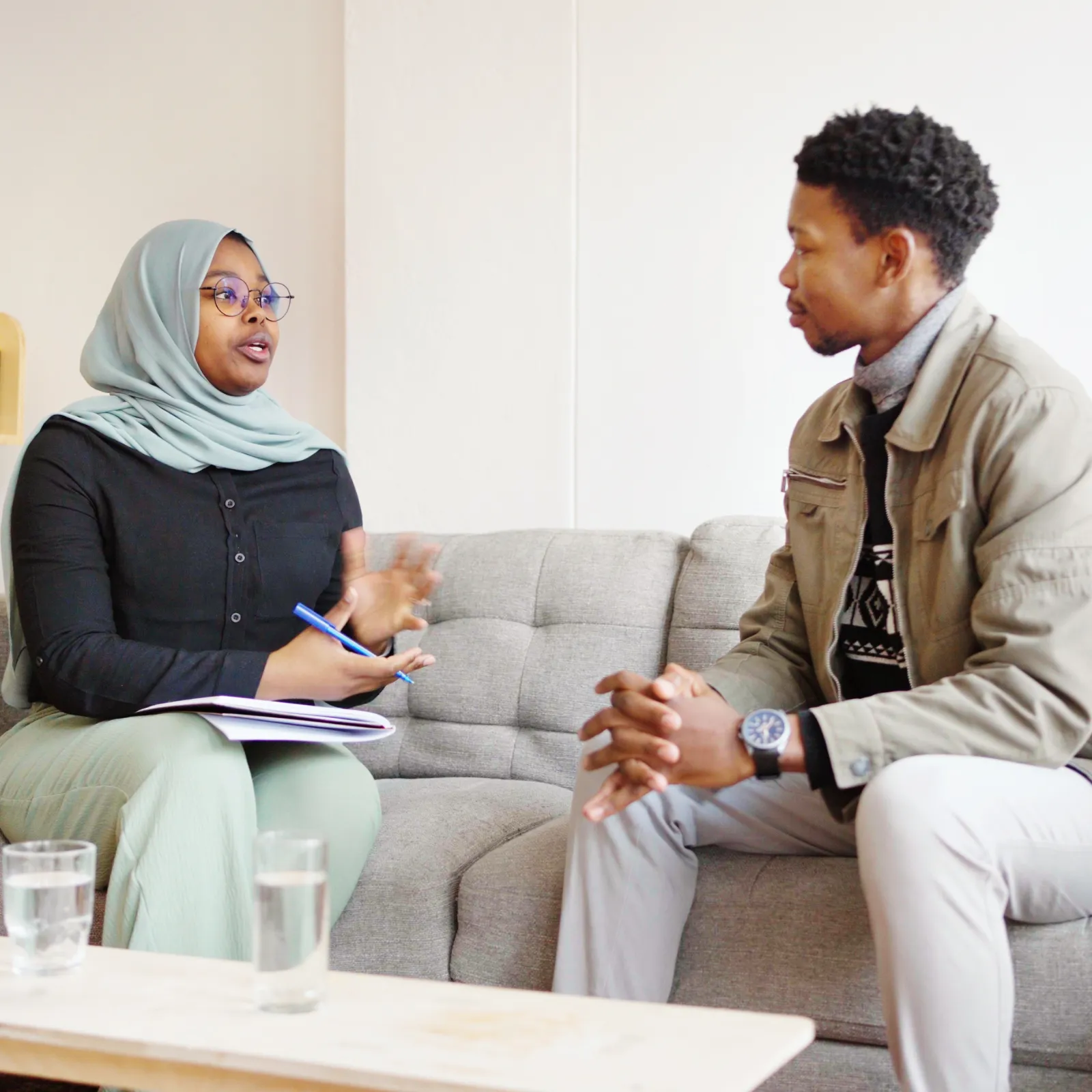 Two people sat on a sofa talking to each other