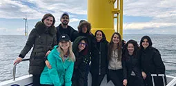 Energy Law students standing next to wind turbine at an ocean windfarm