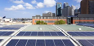 Solar panels on a roof in a city with skyscrapers in the background
