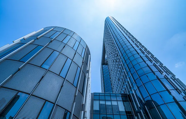 A view looking up from the ground at glass office buildings and a bluesky.