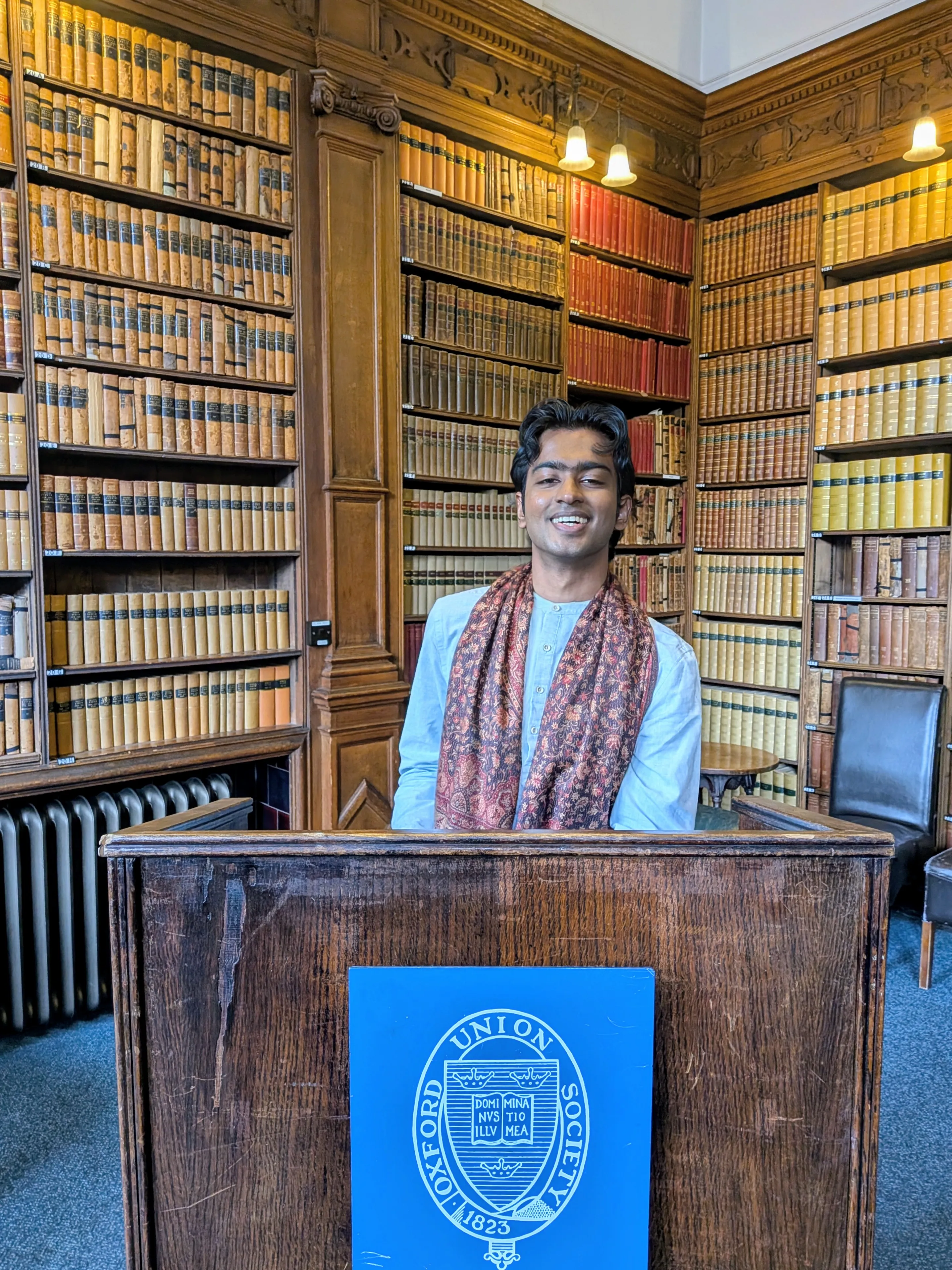 Rehan Meemaduma standing behind a lectern in a library