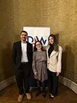 Two students and an academic stood in front of a white display