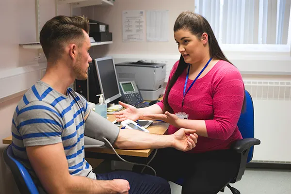 Photograph of a clinician taking a patients blood pressure during a consultation at a GP practice