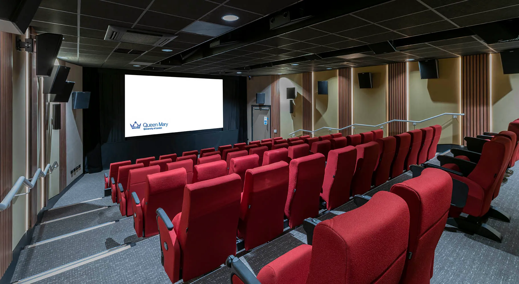 A cinema with raked seating with red seats and a pale yellow walls