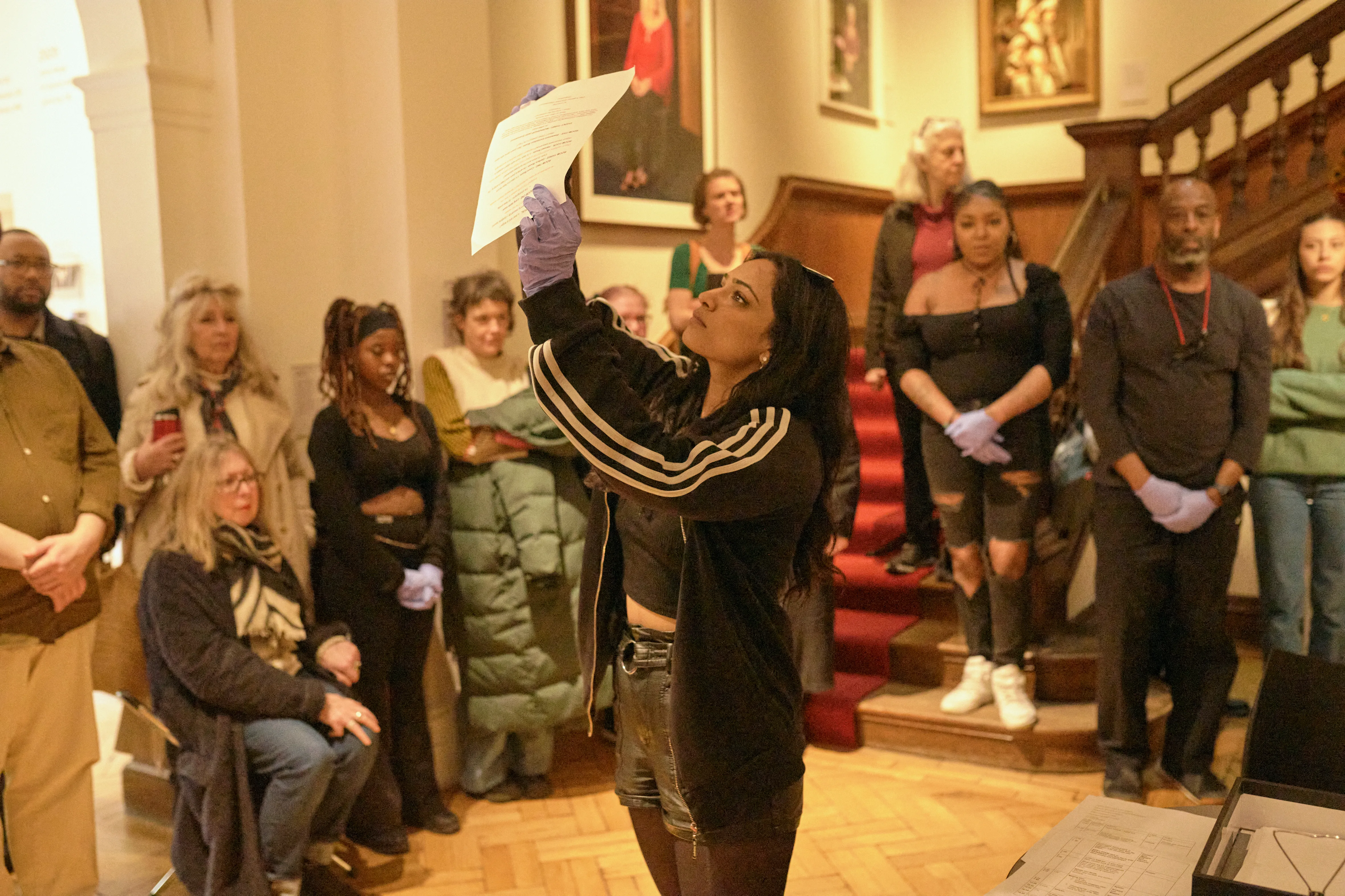 A person wearing gloves holds up a piece of paper as part of a theatre production