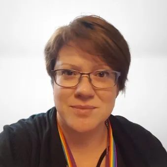 Abigail Mason looking towards camera. Wearing a black top and the background is white.