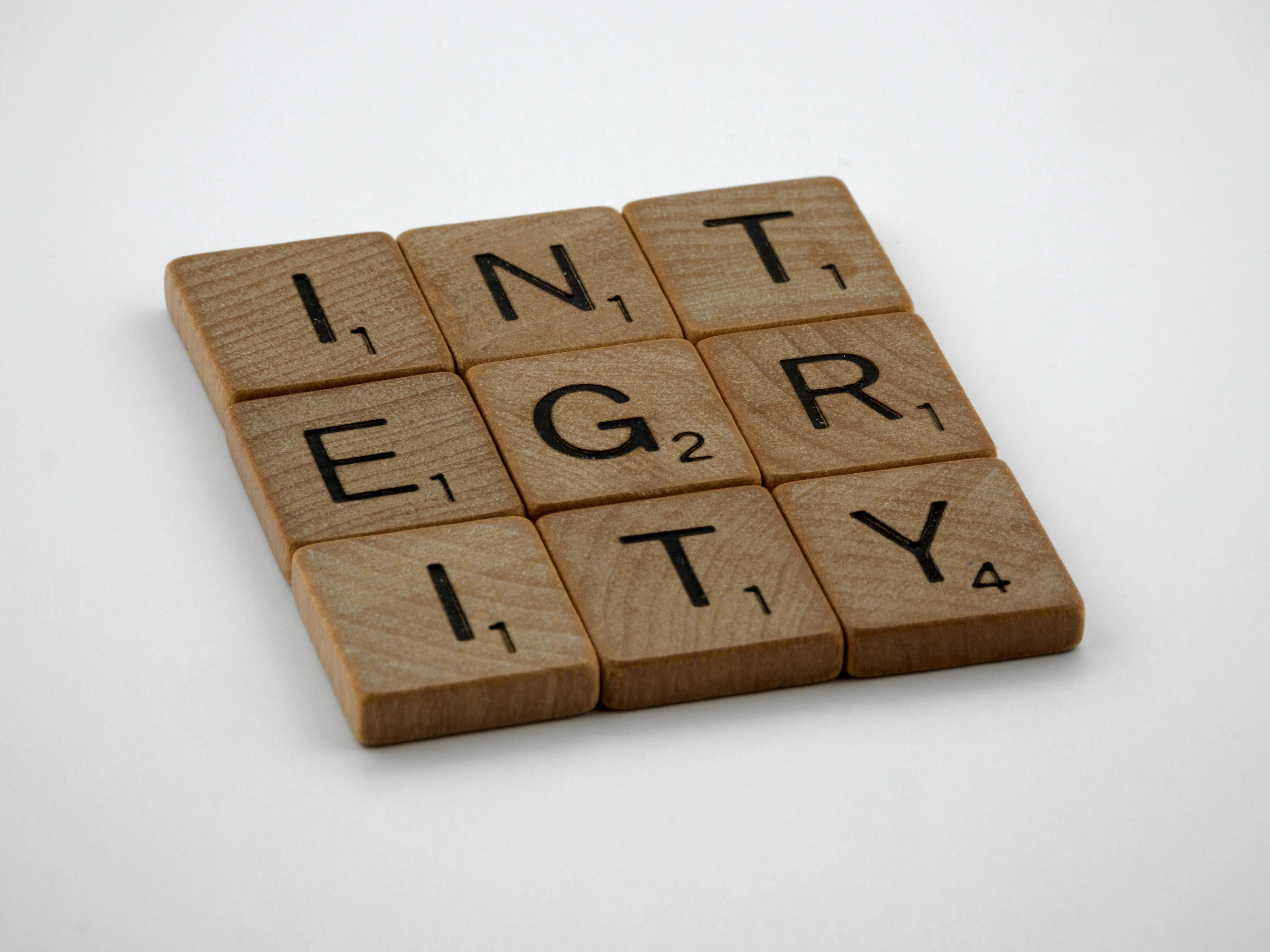 Integrity in written. Each letter is on a tile and they have been laid out in the shape of a square.