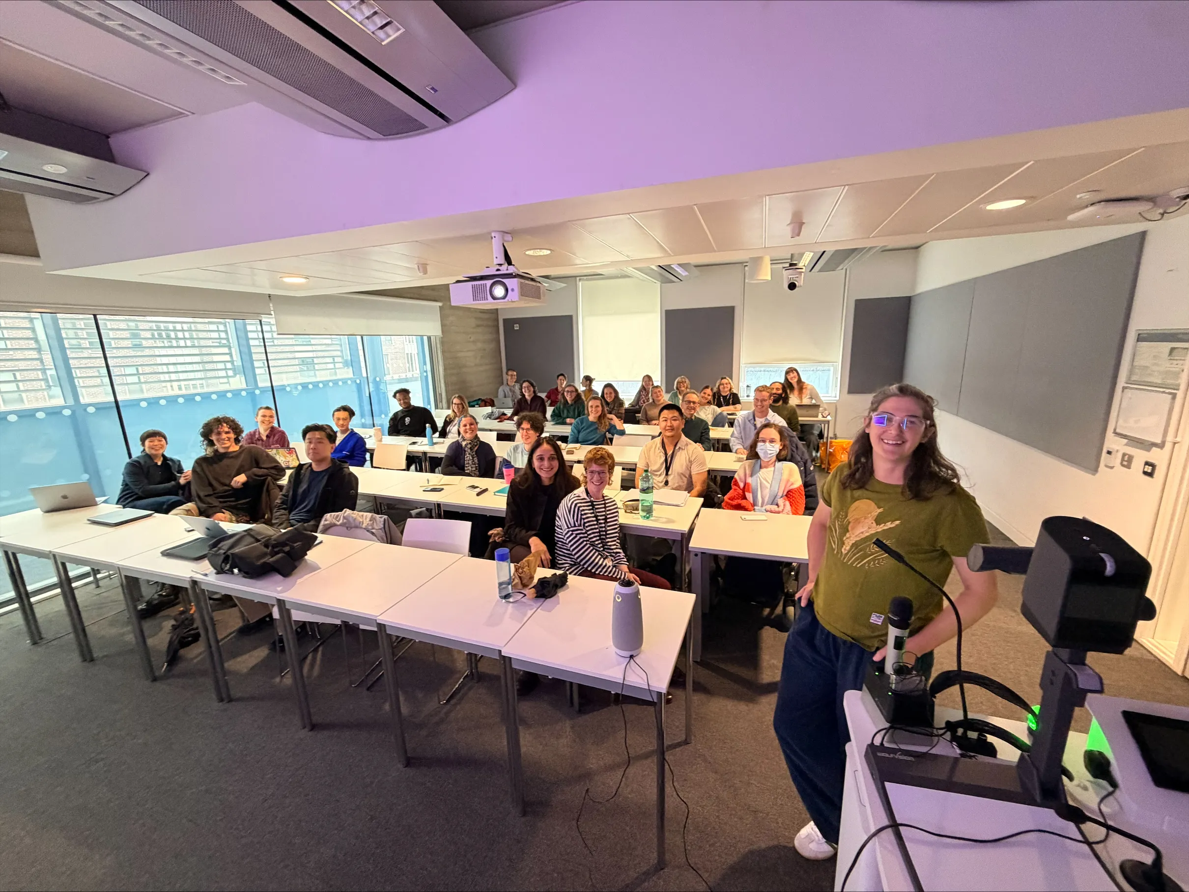 Students, Staff and Amanda Cole smile in a classroom before her guest lecture.