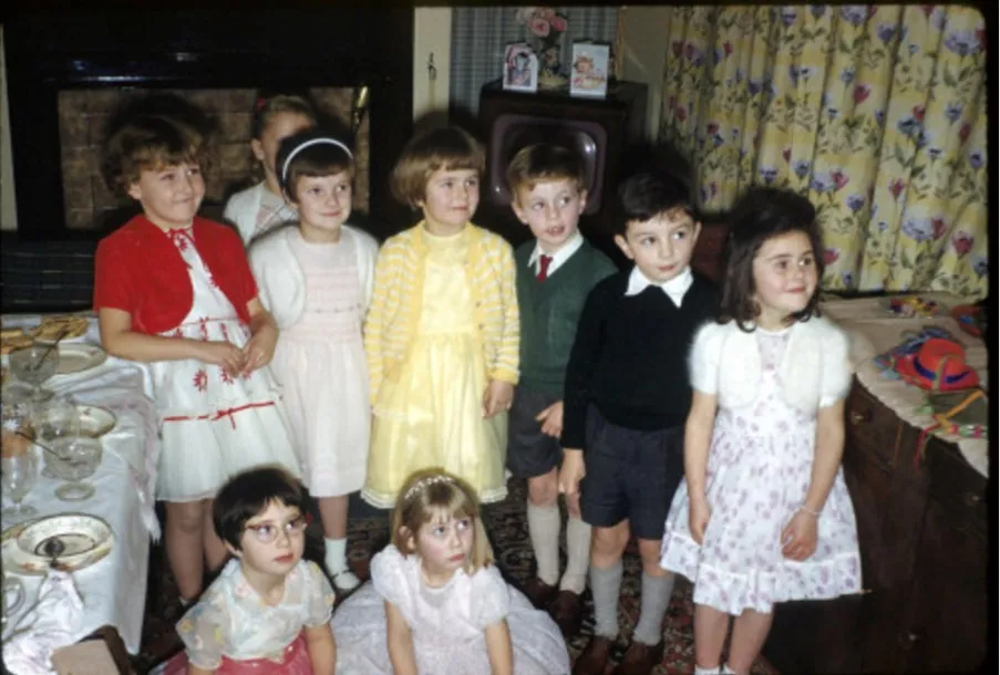 Vintage photograph of children smiling in a living room at a party, from around 1940s or 50s