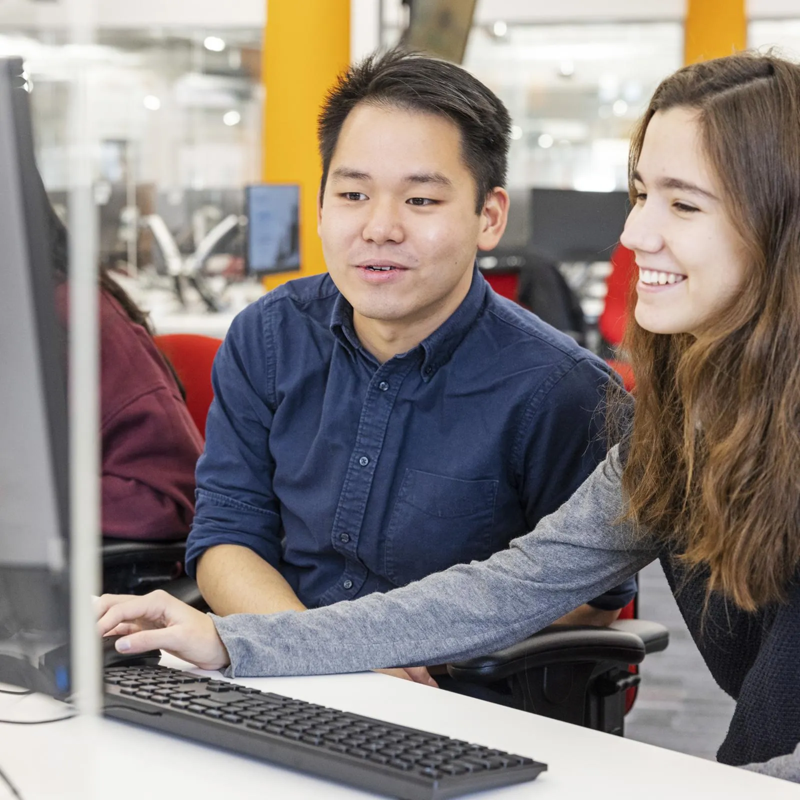 Two students collaborating on a project in front of a laptop