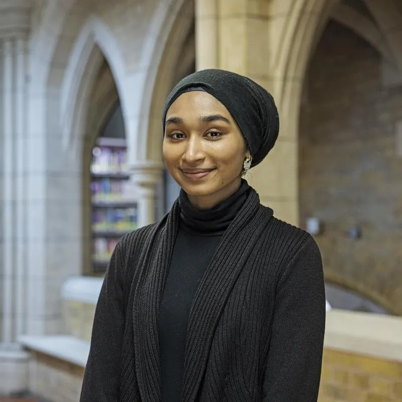 Portrait of a smiling student wearing a black sweater and head scarf.