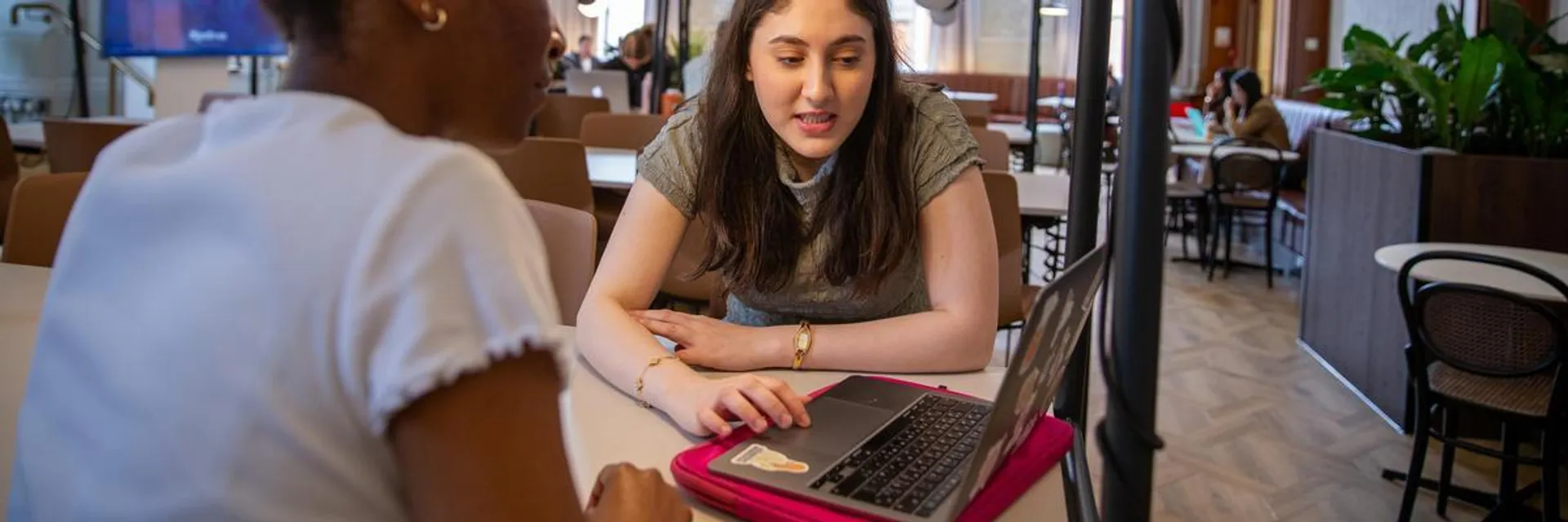 2 students sitting and looking at a laptop