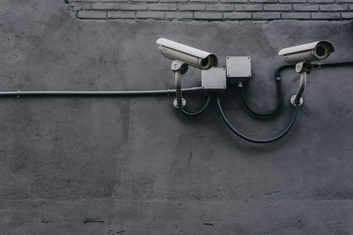 two CCTV cameras on a grey wall