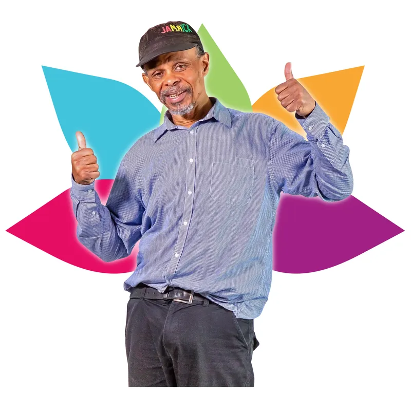 A smiling man giving thumbs-up with both hands in front of a colorful background.