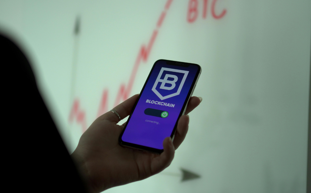 Image of a hand holding a phone with text saying Blockchain