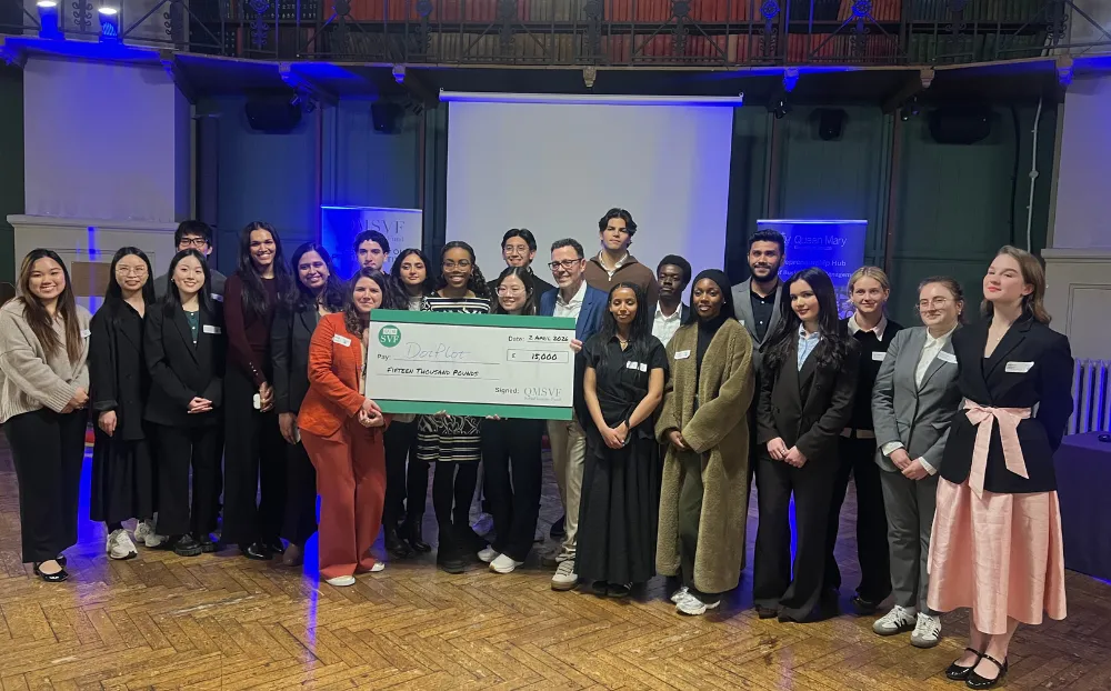 An image of a large group of people gathered on stage holding a cheque of £15,000