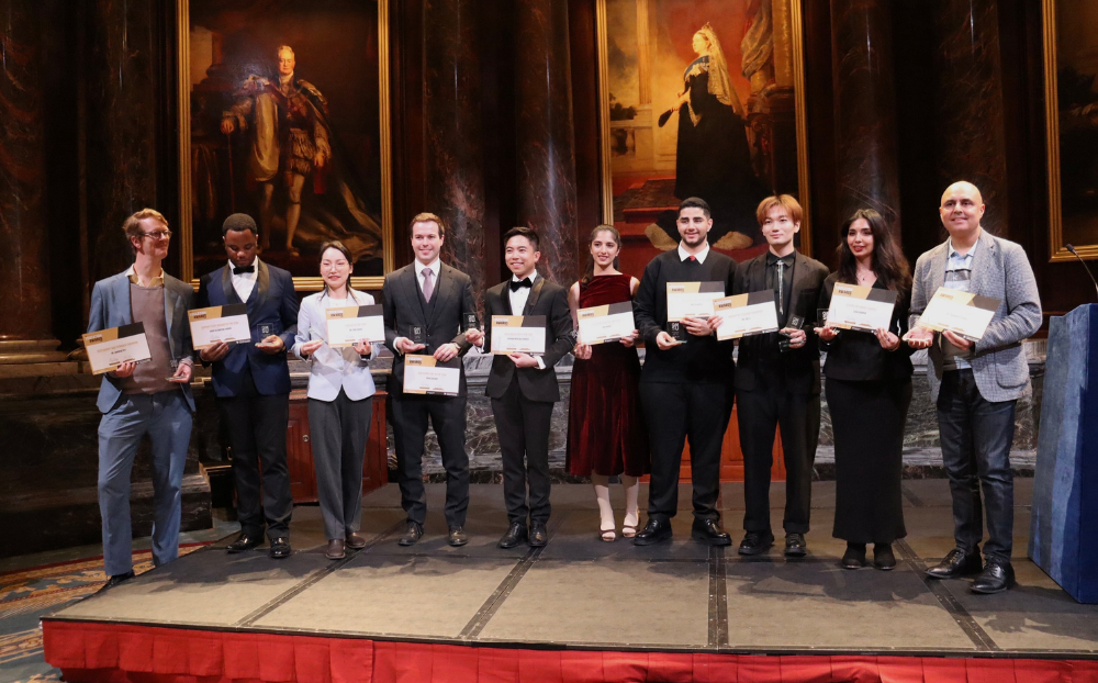 Image of people standing on a stage holding certificates and smiling