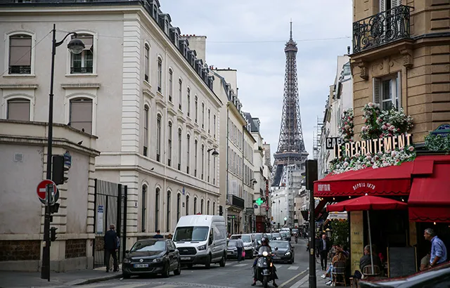 A cafe on a street corner in Paris, France. The Eiffel Tower is visible in the background.