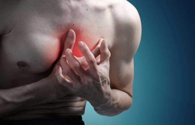 Man clutching chest with both hands, indicating cardiac discomfort symptoms.