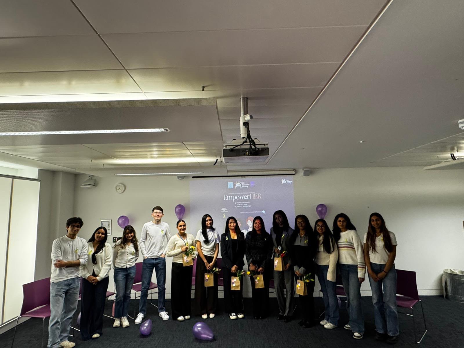 A group of students stand in front of a presentation saying 