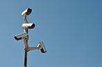Surveillance cameras on a mast against a blue sky