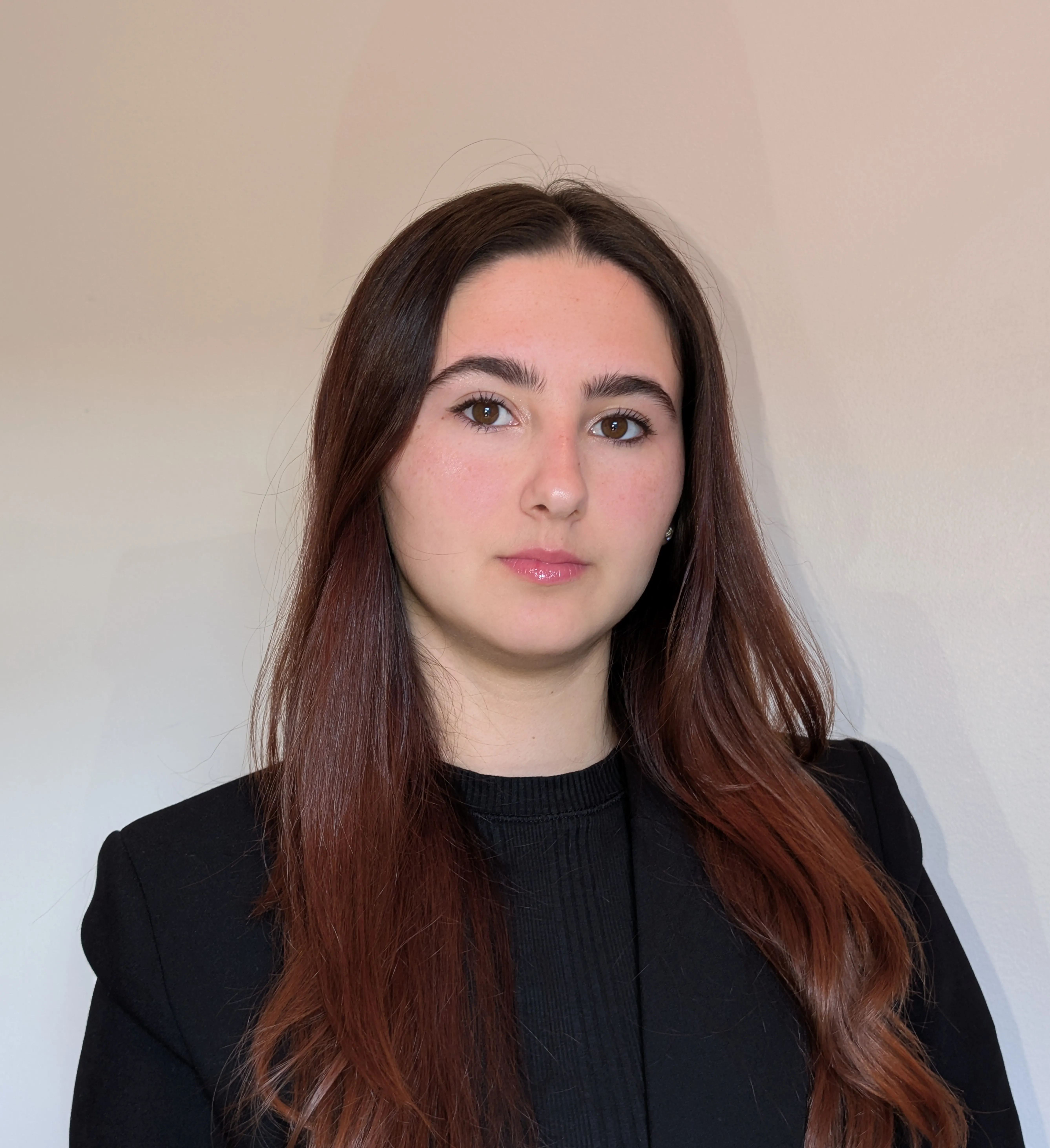 A headshot of a student with brown hair looks at the camera